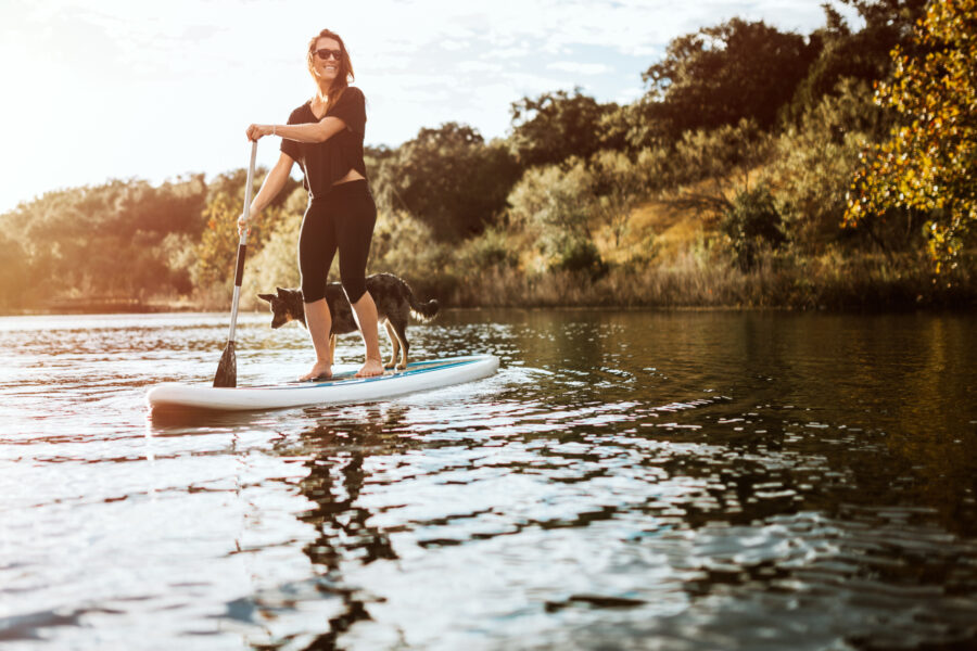 Woman on stand-up paddle with dog on the lake