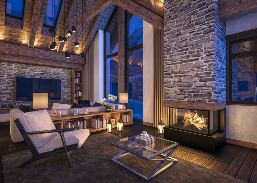Interior of modern rustic cabin-style living room with large windows, exposed stone, and fireplace