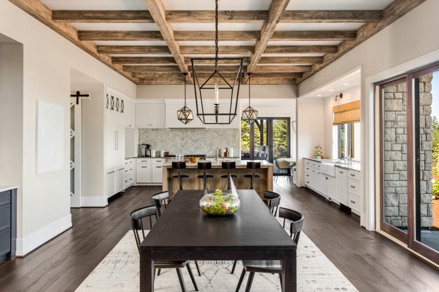Interior view of modern farmhouse style kitchen and dining area with exposed beams and contemporary furniture
