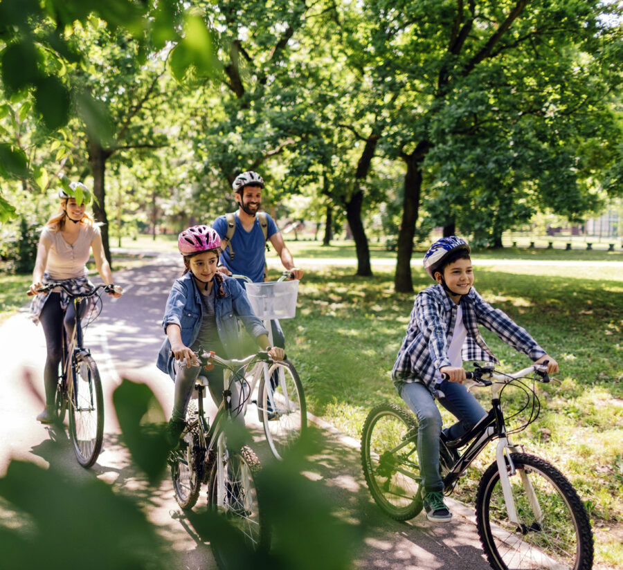 Family of four riding their bicycles through park trail