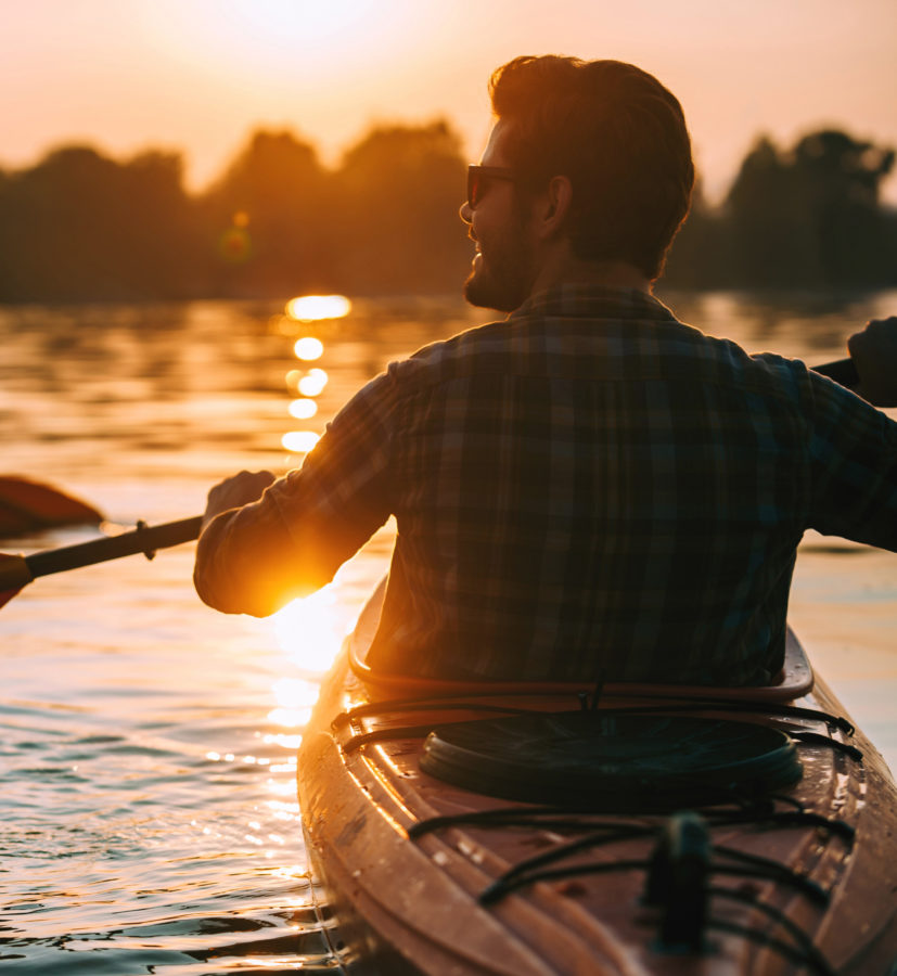 man kayaking on lake at sunset