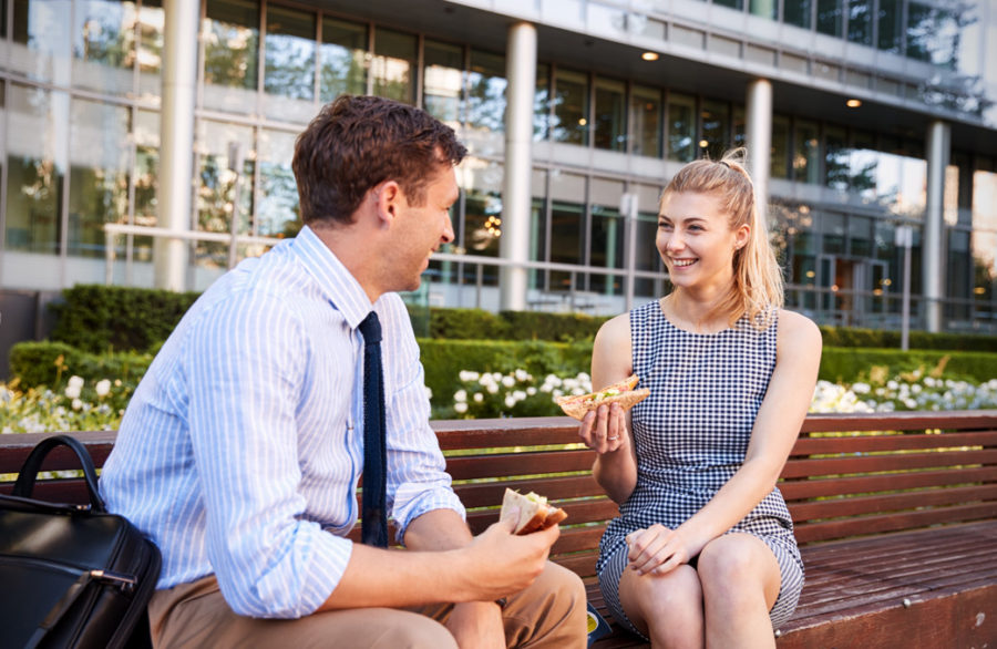 man and woman sitting on bench outside office